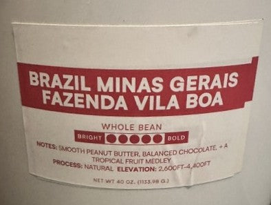A close-up of a white coffee bag label with red text reading 'BRAZIL MINAS GERAIS FAZENDA VILA BOA' and smaller notes below for whole bean bold coffee.