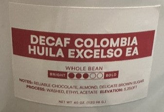 A close-up of a coffee bag label reading 'DECAF COLOMBIA HUILA EXCELSO EA' with red and black text on a white background.