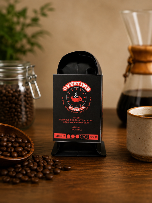A bag of Overtimes Coffee Co. medium roast coffee in a black stand-up pouch with a red and white logo, displayed on a wooden table with coffee beans, a coffee maker, and a cup in a warm, rustic setting.
